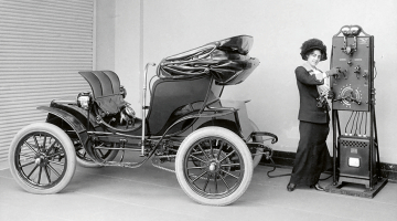 1906. gadā amerikāņu kompānijas Pope ražotais elektroauto tiek uzlādēts ar strāvas ģeneratoru, kas darbināms ar roku