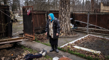 Antoņina Pomazanko savas mājas pagalmā, kur viņa ar plastmasas plēvi un dēļiem piesegusi Krievijas karavīru nošauto meitu.
Foto — The New York Times