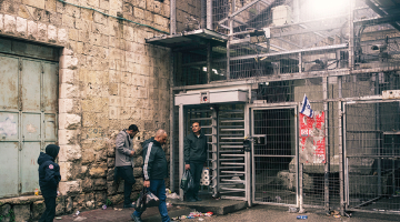 Palestīnieši pēc iepirkšanās pārtikas veikalā gaida pie kāda no Izraēlas ierīkotajiem kontrolposteņiem Hebronā, lai varētu nokļūt mājās.
Foto — The Washington Post