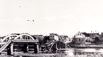 Vācijas armijas saspridzinātais tilts pār Mēmeli Bauskā un degošās Lejas dzirnavas upes dienvidu krastā 1944. gada augustā. Foto – Latvijas Kara muzejs