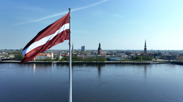Latvijas karogs uz AB dambja un Rīgas panorāma. Foto - Kaspars Nordens, LETA