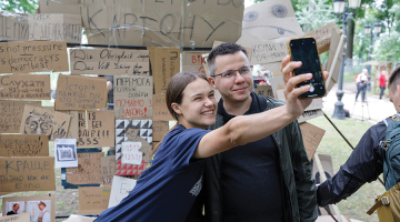 Jaunieši Kijivā pozē pie simboliskas sienas ar plakātiem, kuri tika izmantoti protestos pret pretkorupcijas iestāžu neatkarības likvidēšanu.