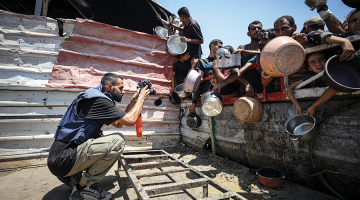 Anass Fteiha 24. jūlijā fotografē cilvēkus, kas ieradušies saņemt ēdienu. Šis attēls viņam radījis daudzas problēmas.
Foto — Khames Alrefi / Anadolu Agency