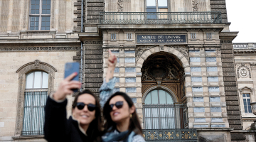 Tūristes pie izsistā loga, pa kuru laupītāji iekļuva Luvras muzejā.