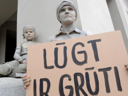 Instalācija "Nemanāma ģimene" - sieviete ar bērnu nokrāsoti ēkas sienas krāsā un saplūst ar apkārtējo vidi. Labdarības projekta "Paēdušai Latvijai" vides akcija, sākot kampaņu "Lūgt ir grūti. Palīdzēt ir viegli". Foto: Ieva Čīka, LETA
