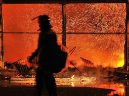 Policists pie degošās rūpnīcas Londonas piepilsētā. Foto: AFP/LETA
