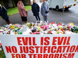 Teroristu nogalinātā britu karavīra Lī Rigbija piemiņai notikuma vietā gulst ziedi un arī plakāti pret terorismu. Foto: EPA/LETA
