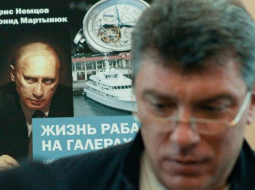 Opozīcijas politiķis Boriss Ņemcovs pozē savas un Leonīda Martiņuka sarakstītās grāmatas par prezidenta Putina privilēģijām "Verga dzīve galerās" vāka fona. Foto: ITAR-TASS/LETA