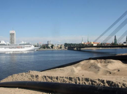 Kruīza kuģis piestātnē Daugavas labajā krastā un smilšu kalns pretējā krastā. Foto: Edijs Pālens, LETA