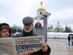 Cilvēki lasa par Ukrainas vēlēšanu rezultātiem. Foto: AFP/LETA