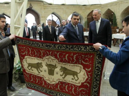 Baku vecpilsētas administrācijas vadītāja vietnieks Samirs Nurijevs (no kreisās) un Latvijas Valsts prezidents Andris Bērziņš šopavasar ekskursijas laikā Baku vecpilsētā apskata Azerbaidžānas meistaru darinātu paklāju. Foto: Ieva Čīka, LETA