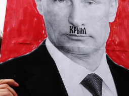 Plakāts ar Krievijas prezidenta Vladimira Putina portretu, kur sejā kā Hitlera ūsiņas ierakstīts Krievijas anektētās teritorijas - Krima - vārds. Foto: AFP/LETA