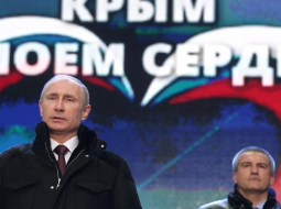 Vladimirs Putins (no kreisās) Krimas aneksijai veltītajā koncertā Sarkanajā laukumā Maskavā. Fonā - Krimas pašieceltais vadītājs Sergejs Aksenovs. Foto: ITAR-TASS/LETA