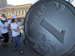 Krievijas prezidenta Putina politikas atbalstītāji pērnvasar sarīkoja akciju "Man tiešām patīk Putins", ripinot divus metrus lielu rubli, kura vērtība krītas. Foto: AFP/LETA