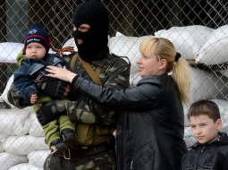Lieldienu ģimenes foto Ukrainas promaskavas separātistu ieņemtajā Slavjanskā. Māte bērnus liek fotografēt kopā ar maskotiem separātistiem pie barikādēm. Foto: AFP/LETA