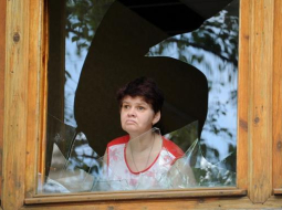 Sieviete Slovjanskā skatās caur sašautu logu. Foto: EPA/LETA