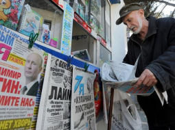 Krimā vīrs pie avīžu kioska lasa Krievijas laikrakstus. Foto: AFP/LETA