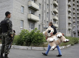 Karš un miers. Ukrainas armijas karavīrs noskatās, kā Austrumukrainas Avdejevkas pilsētiņas iedzīvotājs dodas uz mājām. Foto: AFP/LETA