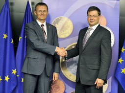 Finanšu ministrs Andris Vilks (no kreisās) un valdības vadītājs Valdis Dombrovskis pozē Briselē pēc paziņojuma par eiro ieviešanu Latvijā. Foto: AFP/LETA