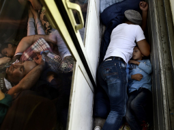 Sīrijas bēgļi guļ vilcienā ceļā no Maķedonijas. Foto: AFP/LETA