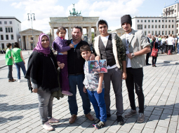 Sīriešu bēgļu ģimene Berlīnē pie Brandenburgas vārtiem pozē: no kreisās - Nada, Noor, Laith Majid Al-Amirij, Taha, Ahmeds un Mustafa. Foto: EPA/LETA