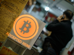 Virtuālā valūta "Bitcoin" - ar to var norēķināties te, rakstīts kādā Honkongas iestādē. Foto: AFP/LETA