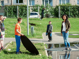 Bolderājas puikas ielenkuši Aminatu fotografēšanas laikā un pat palīdz izgaismot dziedātājas seju.