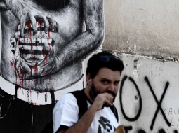 Attēlā redzamais grafiti Atēnās var izrādīties grieķiem atbilstošs - būs krietni jāsavelk jostas. Foto: AFP/LETA