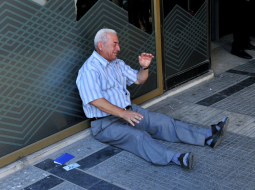 Grieķu pensionārs Giorgoss Hatzifotiadis sēž pie bankas un raud, uzzinājis, ka atļauts izņemt tikai 120 eiro no pensijas. Foto: AFP/LETA
