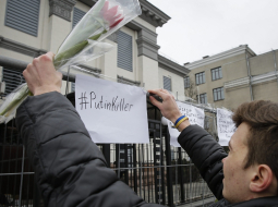 Putins - slepkava. Kāds vīrietis piestiprina uzrakstu pie Krievijas vēstniecības žoga Kijevā pēc Kremļa opozicionāra Borisa Ņemcova slepkavības Maskavā. Foto: AFP/LETA