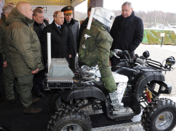 Krievijas prezidents Vladimirs Putins (centrā) un Dmitrijs Rogozins (pa labi) iepazīstas ar militāristu jaunumiem - robotu-karotāju, kas spēj braukt arī ar kvadraciklu. Foto: ITAR-TASS/LETA