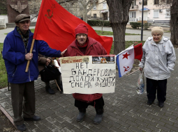 Nemainīgā pārliecība arī šodien Krievijas Ukrainai atņemtajā Sevastopolē - padomju laikus piedzīvojušie tur plakātu ar uzrakstu: "Nē baderoviešiem, nost ar huntu, nāvi fašismam!". Foto: AFP/LETA