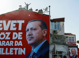 Kāds vīrs Stambulā uzrāpies uz jumta un skandina prezidentu Redžepu Tajipu Erdoganu atbalstošus saukļus. Gaidāmā referenduma kampaņas plakātā rakstīts: «Jā, vārdi un lēmumi pieder tautai.»