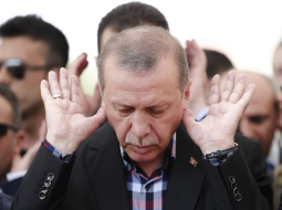 Turcijas prezidents Redžeps Tajips Erdogans lūdzas kapsētā pie militārā apvērsuma mēģinājuma laikā bojāgājušo zārkiem Stambulā. Foto: EPA/LETA