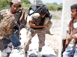 Lībijas armijas karavīri no apšaudes iznes ievainotu biedru. Foto: Reuters/LETA