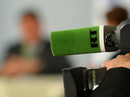 "Russia Today" logo uz mikrofona. Foto: Sputnik/LETA