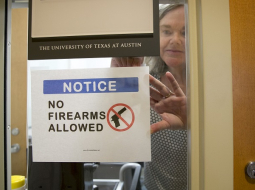 Teksasas universitātes Ostinā antropoloģijas profesore Paulīne Stronga pie sava kabineta durvīm piestiprina norādi, ka te nedrīkst ienākt ar ieročiem. Foto: AP/LETA