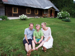 Ainārs, Raitis un Marta savu lauku māju pagalmā.