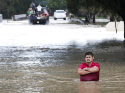 Vīrietis stāv uz applūduša ceļa pie tilta Hjūstonā. Foto: AP/LETA