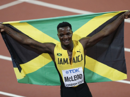 Jamaikas skrējējs Omars Makleods svin uzvaru šovasar 110 m skrējienā. Viņam rokās Jamaikas karogs. Foto: AFP/LETA