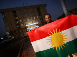 Irākas kurds tur Kurdistānas karogu pie Kurdistānas parlamenta ēkas Arbilā. Foto: AFP/LETA