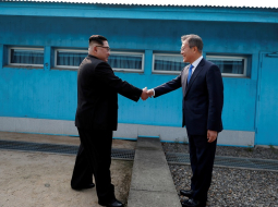 Dienvidkorejas prezidents Muns Džēins sarokojas ar Ziemeļkorejas līderi Kimu Čenunu uz abu valstu robežas. Foto: Reuters/LETA