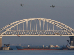 Krievijas iznīcinātāji lido pār Kerčas tiltu, bet krievu kravas kuģis zem tilta noslēdzis ceļu pēc tam, kad Krievija apturēja trīs Ukrainas karakuģus ceļā uz Mariupoles ostu Azovas jūrā cauri Kerčas šaurumam. Foto: REUTERS/Scanpix