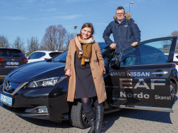 Raksta autore Ieva Jakone
ar dzīvesbiedru pie izmēģinātā elektromobiļa.
Foto — Lauris Aizupietis