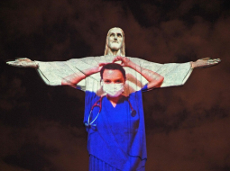Slavenā Jēzus Kristus statuja Riodežaneiro Lieldienās tika izgaismota mediķa virsvalkā. Ārsti fotgrafējās uz tās fona. Foto: AFP/Scanpix/LETA