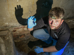 Latvijas Okupācijas muzeja vēsturnieks Jānis Goldšmits rāda atrasto patronas čaulīti. Foto: Aivars Reinholds, Latvijas Okupācijas muzejs