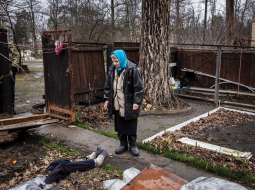 Antoņina Pomazanko savas mājas pagalmā, kur viņa ar plastmasas plēvi un dēļiem piesegusi Krievijas karavīru nošauto meitu.
Foto — The New York Times