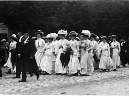 Rīga, 1910. gada 18. jūnijs. Rīgas latviešu pilsonības dāmas un kungi V Vispārējo latviešu dziesmu svētku gājienā. Svētki notika neapbūvētā teritorijā tagadējās Emiļa Melngaiļa un Hanzas ielas rajonā. 
Fotogrāfs nezināms. Latvijas Nacionālās bibliotēkas krājums
