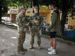 Seržanti Serhijs Stepaņuks (pa kreisi) un Mihailo Pavlovs pārbauda kāda uz ielas sastapta jauna vīrieša personības dokumentus Ukrainas rietumu pilsētā Užhorodā. Pēc frontē gūtiem ievainojumiem abi karavīri tagad nodarbināti militārā iesaukuma centrā