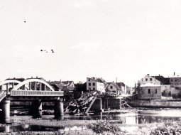 Vācijas armijas saspridzinātais tilts pār Mēmeli Bauskā un degošās Lejas dzirnavas upes dienvidu krastā 1944. gada augustā. Foto – Latvijas Kara muzejs